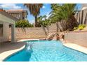 Enjoy a refreshing pool with a waterfall feature and lush tropical landscaping in this backyard oasis at 8326 Mount Nido Dr, Las Vegas, NV 89147