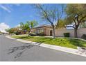 Street view of a well-maintained home with desert landscaping, mature trees, and lush green lawns at 10089 Clifton Forge Ave, Las Vegas, NV 89148