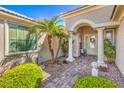 Inviting front entrance with double doors, stone pathway, columns, and mature landscaping at 10314 Premia Pl, Las Vegas, NV 89135