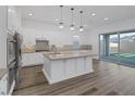 Modern kitchen with white cabinetry, stainless steel appliances, a large center island, and sliding glass doors to the backyard at 11617 Peregrine Point Ct, Las Vegas, NV 89138
