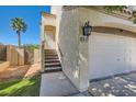 Side angle view of a two-story home with stucco walls, a two-car garage, and a well-manicured lawn at 1672 Cloister Ave, Henderson, NV 89014