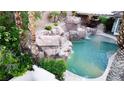 Backyard pool boasts rock waterfalls and lush greenery, creating a private, tranquil oasis at 764 Ricota Ct, Henderson, NV 89012