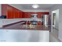 Well-lit kitchen boasts stainless steel appliances, rich wood cabinetry, and ample counter space at 9148 Alluring Ave, Las Vegas, NV 89149