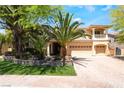 Inviting home with lush landscaping, palm trees, and a brick driveway leading to a three-car garage at 11237 Campsie Fells Ct, Las Vegas, NV 89141