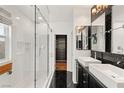 Modern bathroom featuring double sinks, black marble floors, and a glass-enclosed shower with built in bench at 11578 Suburban Rd, Las Vegas, NV 89135