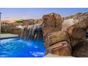 A stunning rock waterfall feature enhances the beauty of the pool, creating a natural and soothing atmosphere at 12219 Crystal Shore Ave, Las Vegas, NV 89138