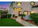 A covered front entrance with decorative columns, manicured landscaping, and an artificial lawn at 2589 Sun Reef Rd, Las Vegas, NV 89128