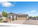 Single-story home with a brick driveway, a two-car garage, desert landscaping, and a decorative gate at 7070 Cinder Horse St, Las Vegas, NV 89131