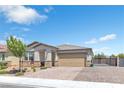 Single-story home with a brick driveway, a two-car garage, desert landscaping, and a decorative gate at 7070 Cinder Horse St, Las Vegas, NV 89131