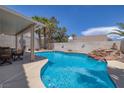 Beautiful pool with rock waterfall, a covered patio, and lush landscaping for relaxing outdoor living at 9516 Belgate Ct, Las Vegas, NV 89129