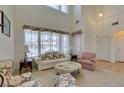 Bright living room featuring high ceilings, large windows, and a traditional style with carpeted floors at 10290 Marion Morrison Ct, Las Vegas, NV 89183
