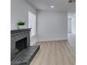 Bright living room featuring a black brick fireplace and neutral walls with light wood floors at 1744 La Cruz Dr, Henderson, NV 89014