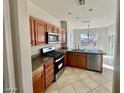 Bright kitchen with wood cabinets, stainless steel appliances, stone counters, and tile floors at 2749 Invermark St, Henderson, NV 89044