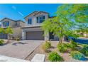 Traditional two-story home with lush front yard landscaping and a brick driveway to a two-car garage at 6442 Kobe Knoll Ct, Las Vegas, NV 89141