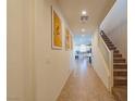 Light-filled hallway featuring tile floors, staircase, and a glimpse of the kitchen with white cabinetry at 6442 Kobe Knoll Ct, Las Vegas, NV 89141