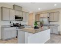 Well-lit kitchen with gray cabinets, stainless steel appliances, granite counters, and an island with a breakfast bar at 7246 Dazzle Point St, North Las Vegas, NV 89084