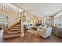 Elegant living room with staircase, neutral color palette, large windows and access to the dining room at 8104 Wispy Sage Way, Las Vegas, NV 89149