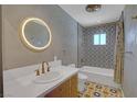 Stylish bathroom with geometric tile, vanity with gold fixtures, and a circular mirror at 819 Bracken Ave, Las Vegas, NV 89104