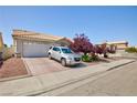 Traditional home featuring a two-car garage and lush landscaping in front at 9091 W Viking Rd, Las Vegas, NV 89147
