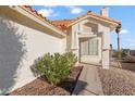 Close-up of a home's facade, featuring stucco walls, a decorative window, and manicured desert landscaping at 2285 Carved Canyon Ln, Laughlin, NV 89029
