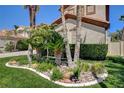 Lush front yard featuring manicured greenery, palm trees, rock features, and decorative curbing at 2388 Kenneth Ave, Henderson, NV 89052