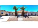 Close-up of a house featuring xeriscaping, concrete steps, and a double-door entrance framed by palm trees at 4119 Meadowglen Cir, Las Vegas, NV 89121