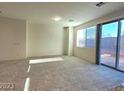 Bright living room with neutral walls, large windows, and sliding glass doors leading to outdoor space at 5817 Bonita Rose St, Las Vegas, NV 89113