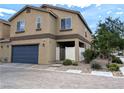 Two-story home featuring a blue garage door, gated entry, and low maintenance desert landscaping at 6168 Scarlet Leaf St, Las Vegas, NV 89148