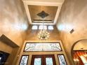 Foyer features soaring ceilings, decorative molding, ornate chandelier, and custom iron accents on the double entry doors at 7625 Coley Ave, Las Vegas, NV 89117