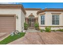 Front entrance with iron gate, potted plants, and tan stucco exterior at 10408 Mezzanino Ct, Las Vegas, NV 89135