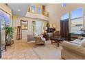 Bright living room with two-story ceilings, large windows, and a view of the upper-level balcony at 11132 Ferragamo Ct, Las Vegas, NV 89141