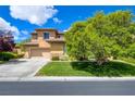 Inviting stucco two-story home with a well-manicured lawn, mature trees, and a spacious driveway and 2-car garage at 17 Stonemark Dr, Henderson, NV 89052