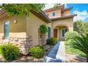 Charming home exterior featuring stone accents, a well-maintained landscape, and an inviting archway leading to the front door at 17 Stonemark Dr, Henderson, NV 89052