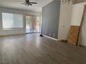 Spacious living room with window and sliding glass door offering natural light, wood-look flooring, and ceiling fan at 2803 Exulted Valley Ave, North Las Vegas, NV 89032