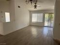 Open-concept living room with high ceilings, neutral paint, window, sliding glass door, and wood-look flooring at 2803 Exulted Valley Ave, North Las Vegas, NV 89032