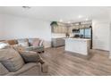 Open-concept living room with a modern kitchen featuring stainless steel appliances and a breakfast bar at 3585 Arcadian Sea St, Las Vegas, NV 89106