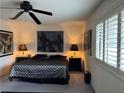 This bedroom features a ceiling fan, a patterned bedspread, and a window with shutter blinds at 4662 Kelly Barry Way, Las Vegas, NV 89121