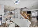 Open-concept dining area with stairs, a modern white table, and wood-look floors at 5024 Starfinder Ave, Las Vegas, NV 89108