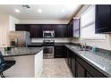 Modern kitchen featuring stainless steel appliances, granite countertops, and dark cabinetry at 6412 Dimatteo St, Las Vegas, NV 89148