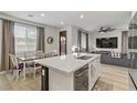 Open-concept kitchen and living room with modern lighting, dining table, and large windows with natural light at 7122 Red Gulch St, North Las Vegas, NV 89084
