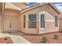 Close up of the exterior featuring a double door entrance, multiple windows, and desert landscaping at 8664 Frasure Falls Ave, Las Vegas, NV 89178