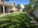 Expansive backyard featuring a covered patio, lush green lawn, and mature landscaping at 1100 Cypress Ridge Ln, Las Vegas, NV 89144