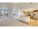 Open living room and kitchen with large windows, carpet and hardwood flooring, and a breakfast bar at 3930 University Center Dr # 312, Las Vegas, NV 89119