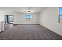 Spacious living room features neutral carpeting, a modern ceiling fan, and bright natural light at 6772 Violet Cascade Ave, Las Vegas, NV 89156