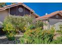 Landscaped front yard with vibrant blooming bushes and a well maintained terra cotta tile roofline at 2704 Miraflores Ave, Las Vegas, NV 89102