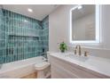 Stylish bathroom with blue tiled shower, bathtub, modern vanity, quartz countertop, and an illuminated mirror at 40 Laswell St, Henderson, NV 89015