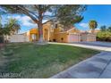Two-story home boasting a lush green lawn and a mature tree, providing ample shade and curb appeal at 4209 Glass Lantern Dr, North Las Vegas, NV 89032