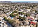 Expansive aerial view of the property surrounded by mature trees, other homes, and the distant mountains at 5715 Gilbert Ln, Las Vegas, NV 89130