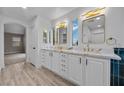 Bright bathroom with double vanity sinks, modern lighting and mirrors, with wood flooring at 575 Dusty Palms Ln, Henderson, NV 89052
