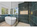 Bright bathroom featuring a soaking tub, glass shower, and modern tiling at 575 Dusty Palms Ln, Henderson, NV 89052